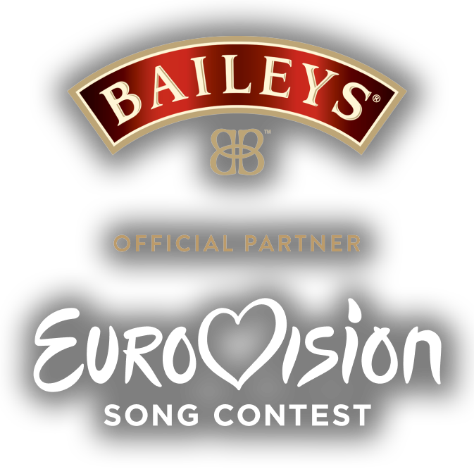 Three Eurovision cocktails with chocolate toppings alongside a Baileys Original Irish Cream bottle in a festive living room table with disco balls, popcorn and celebratory decorations in time for the Eurovision Song Contest celebrations. 